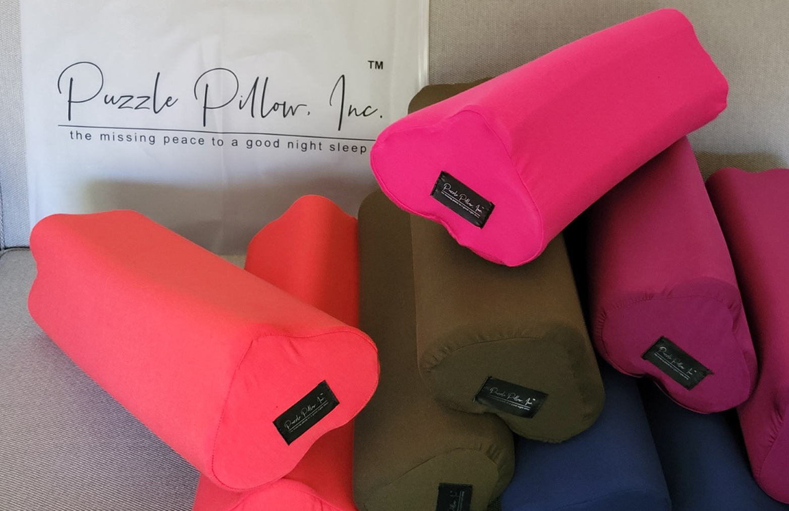 Colorful puzzle pillows with 'Puzzle Pillow, Inc.' branding on a neutral background.